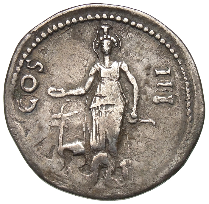 Hadrian reverse — Artemis steht in der Vorderansicht. Sie hält in ihrer l. Hand einen Bogen und in der erhobenen r. Hand eine Schale (patera) über eine nach l. gewandte Hirschkuh. Zu ihren Füßen ist die Schlange der Cista mystica des überprägten Untertyps sichtbar.