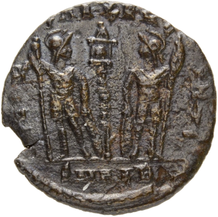 Constantine I reverse — Two soldiers, helmeted, draped, cuirassed, standing facing each other, each holding reversed spear in outer hand and resting inner hand on shield; between them, a standard