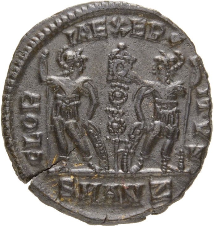 Constantine I reverse — Two soldiers, helmeted, draped, cuirassed, standing facing each other, each holding reversed spear in outer hand and resting inner hand on shield; between them, a standard