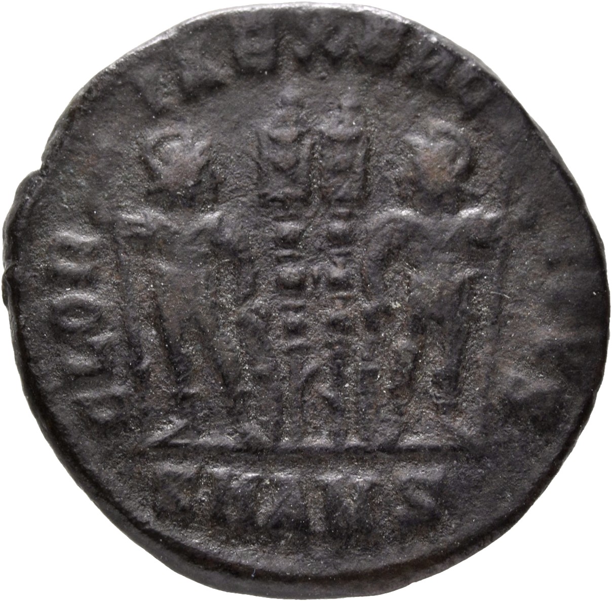 Constantine I reverse — Two soldiers, helmeted, draped, cuirassed, standing facing each other, each holding reversed spear in outer hand and resting inner hand on shield; between them, two standards