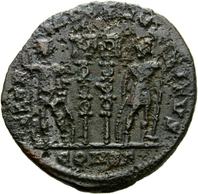 Constantine I reverse — Two soldiers, helmeted, draped, cuirassed, standing facing each other, each holding reversed spear in outer hand and resting inner hand on shield; between them, two standards
