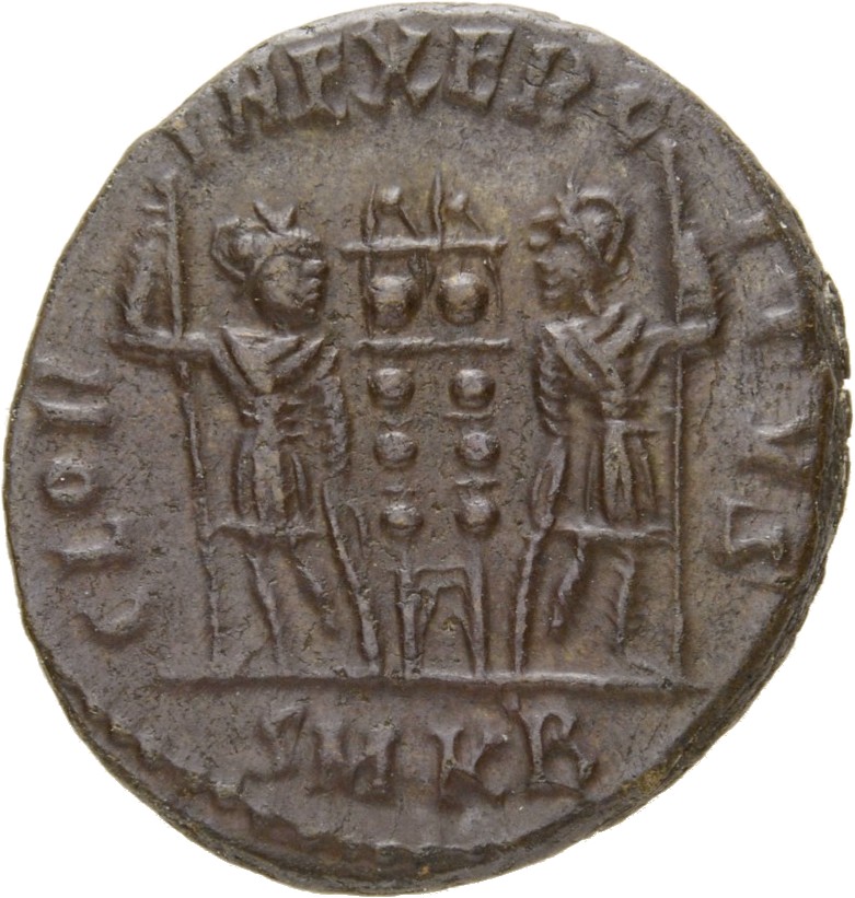 Constantine I reverse — Two soldiers, helmeted, draped, cuirassed, standing facing each other, each holding spear in outer hand and resting inner hand on shield; between them, two standards