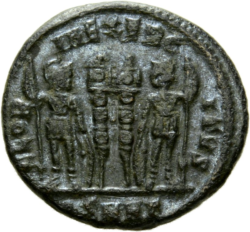 Constantine I reverse — Two soldiers, helmeted, draped, cuirassed, standing facing each other, each holding spear in outer hand and resting inner hand on shield; between them, two standards