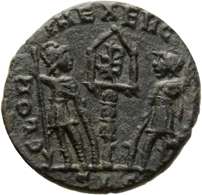 Constantine I reverse — Two soldiers, helmeted, draped, cuirassed, standing facing each other, each holding reversed spear in outer hand and resting inner hand on shield; between them, a standard