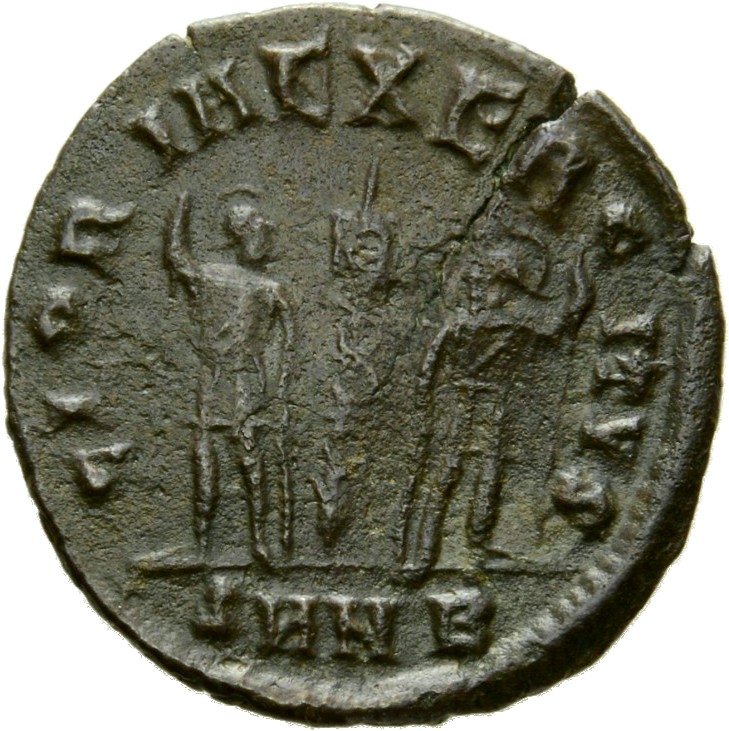 Constantine I reverse — Two soldiers, helmeted, draped, cuirassed, standing facing each other, each holding reversed spear in outer hand and resting inner hand on shield; between them, a standard