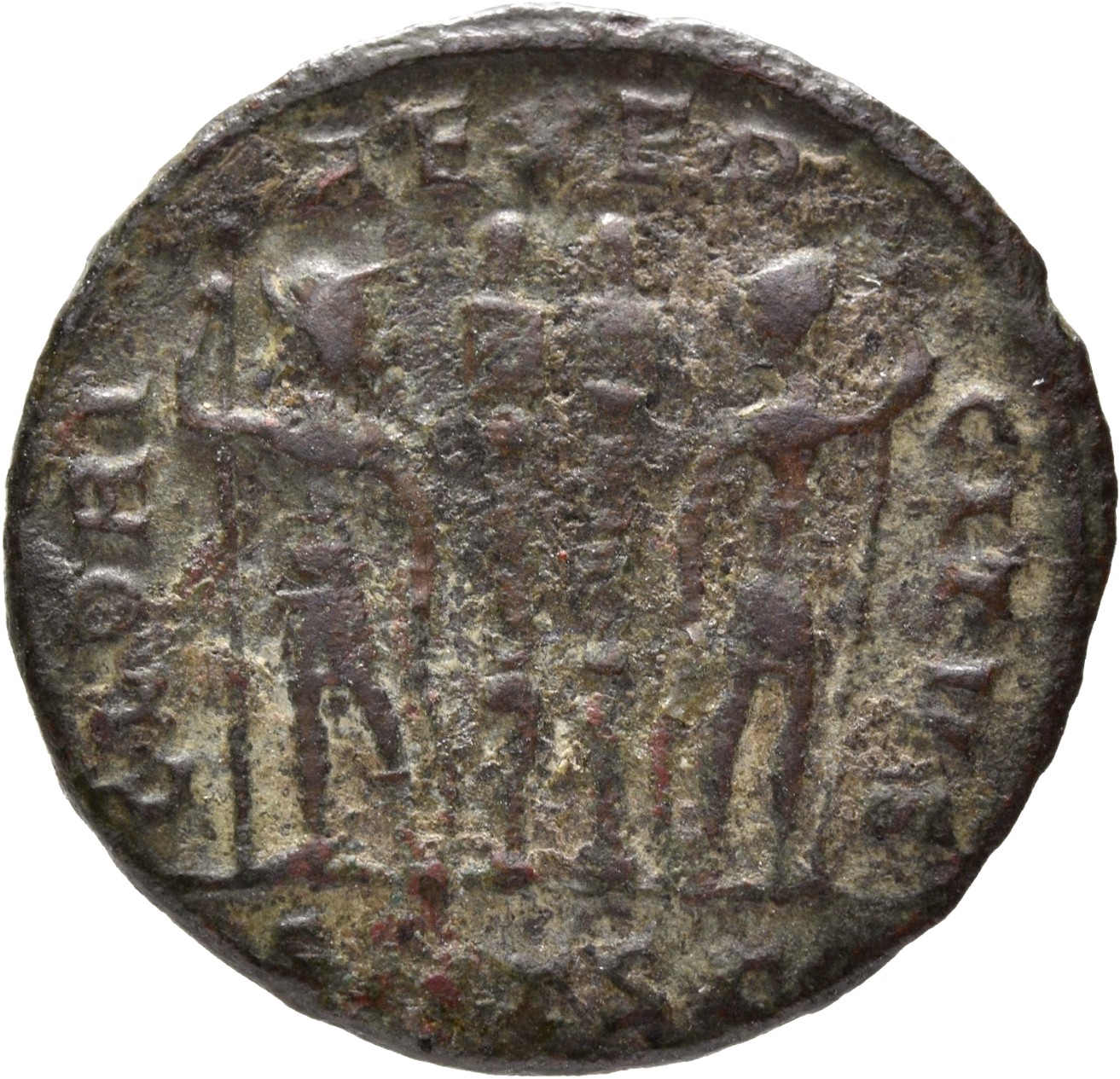 Constantine I reverse — Two soldiers, helmeted, draped, cuirassed, standing facing each other, each holding reversed spear in outer hand and resting inner hand on shield; between them, two standards