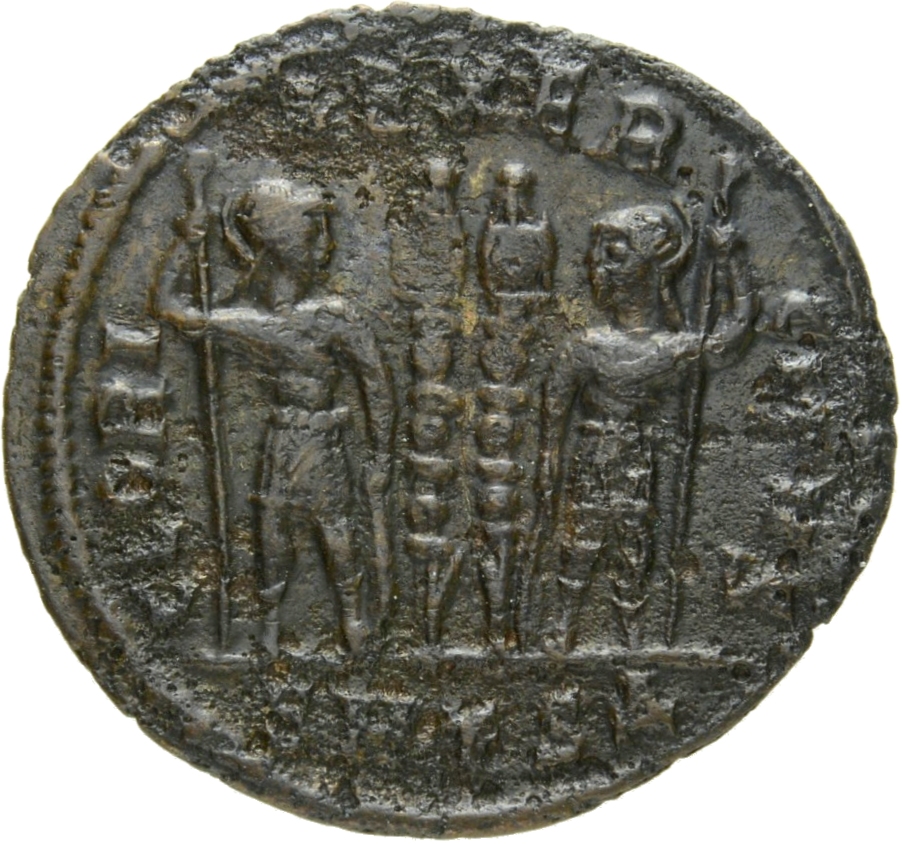 Constantine I reverse — Two soldiers, helmeted, draped, cuirassed, standing facing each other, each holding reversed spear in outer hand and resting inner hand on shield; between them, two standards