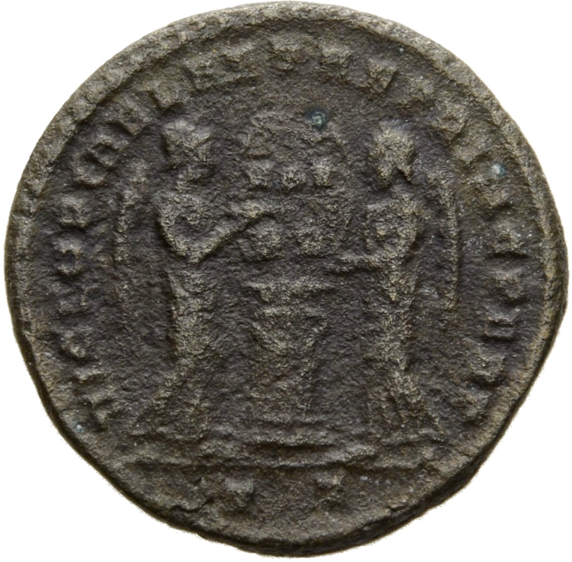 Constantine I reverse — Two Victories, winged, draped, facing each other, holding a shield inscribed VOT/PR supported by an altar