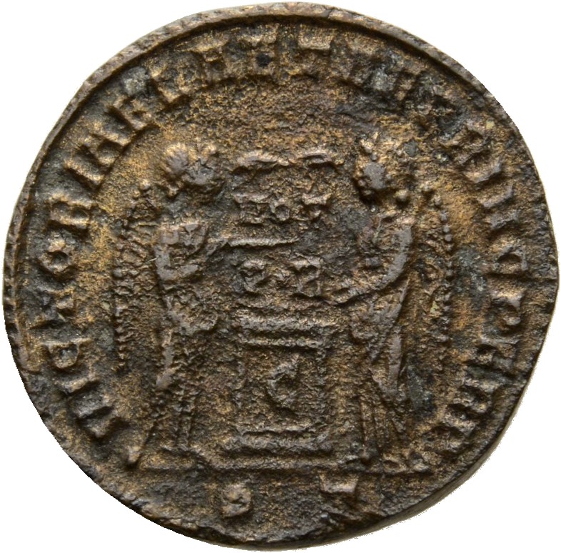 Constantine I reverse — Two Victories, winged, draped, facing each other, holding a shield inscribed VOT/PR supported by a column